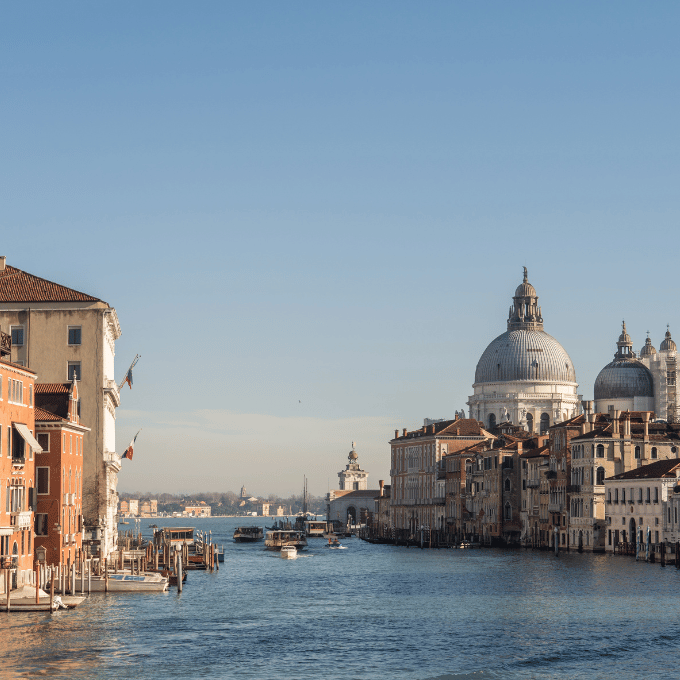 Vue pittoresque depuis un toit-terrasse sur les canaux et les toits de Venise au coucher du soleil, évoquant les meilleurs lieux de séjour et de restauration durant la Mostra de Venise.