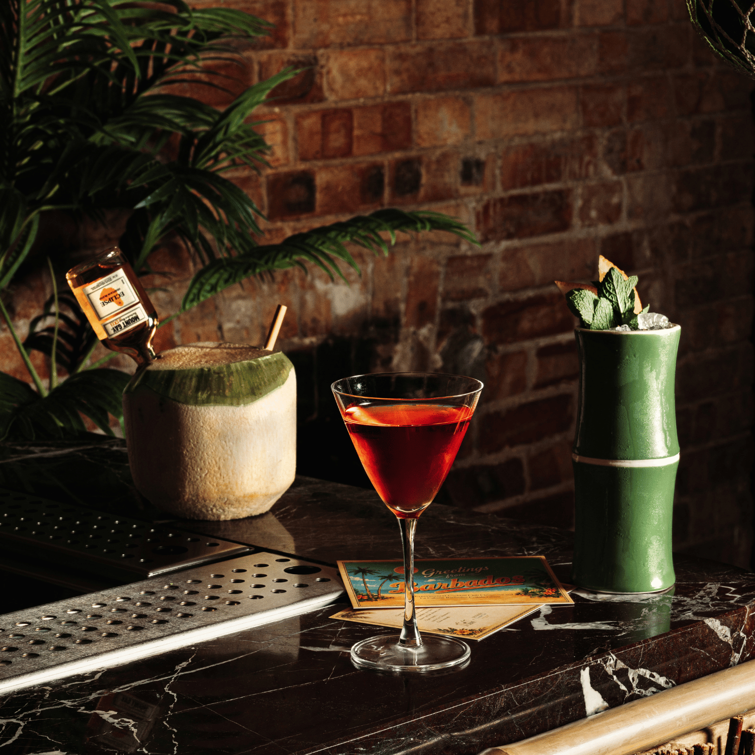 Deux barmans préparant des cocktails derrière un bar garni de bouteilles d'alcool et de verres.