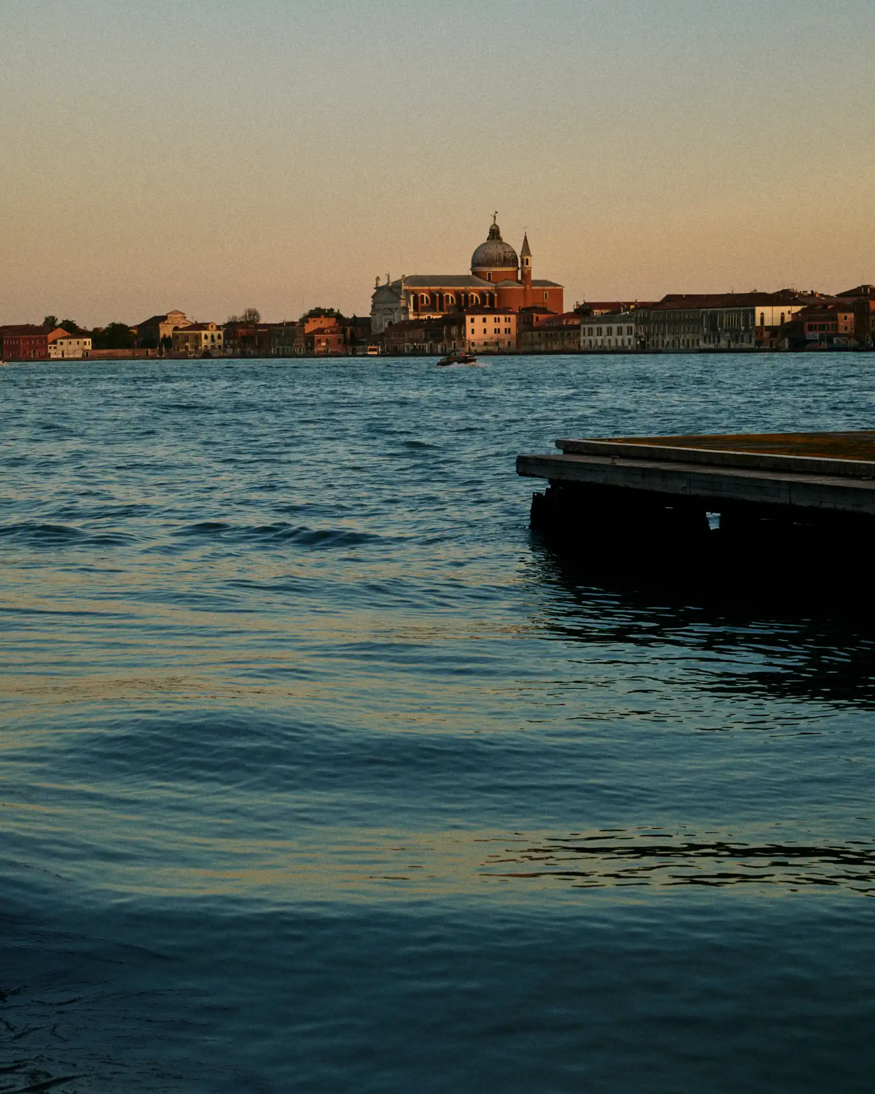 Waterfront view of a coastal town with historic buildings under a clear evening sky.