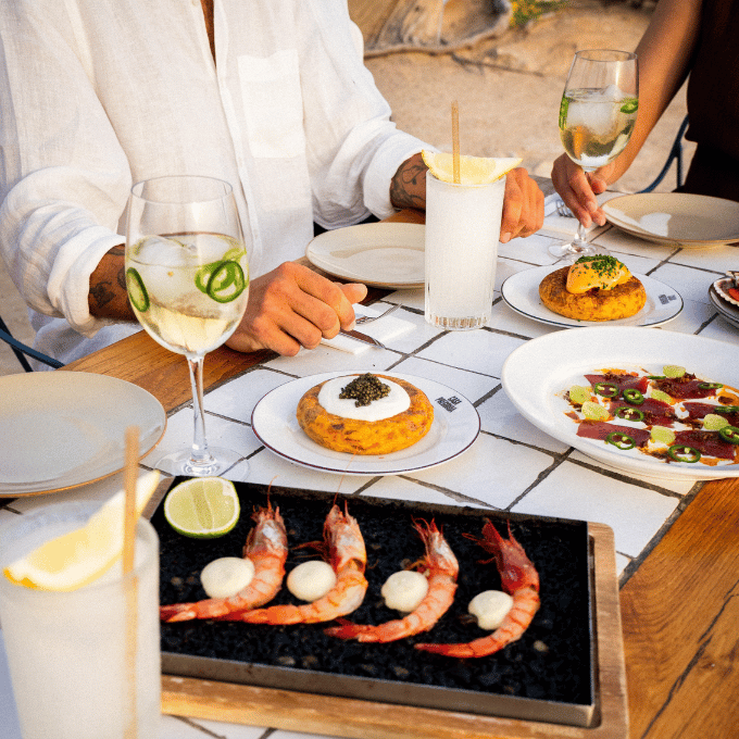Mesa preparada para una cena frente al mar con cócteles durante una velada en Ibiza.