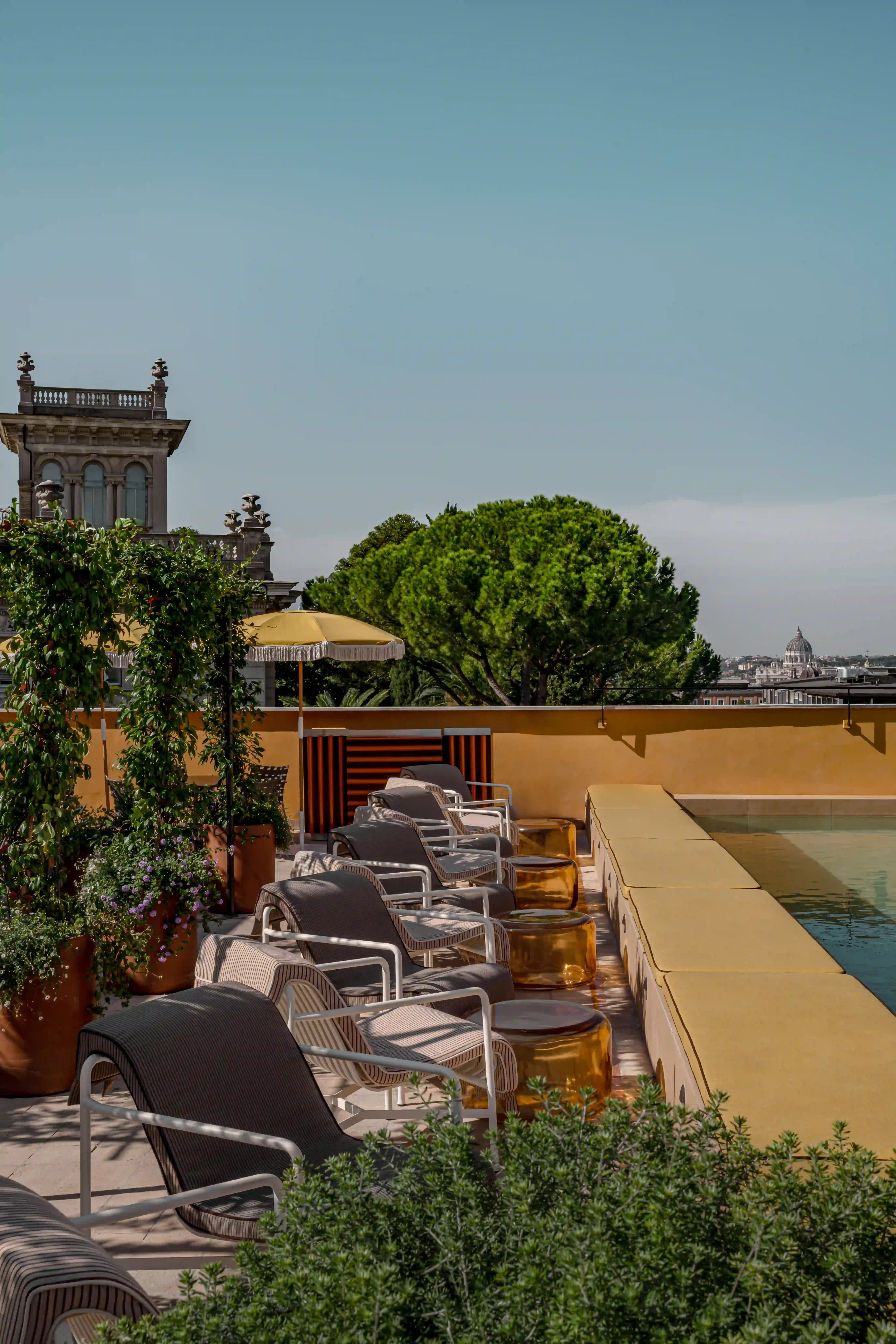 A swimming pool terrace lined with lounge chairs and decorative sun umbrellas.