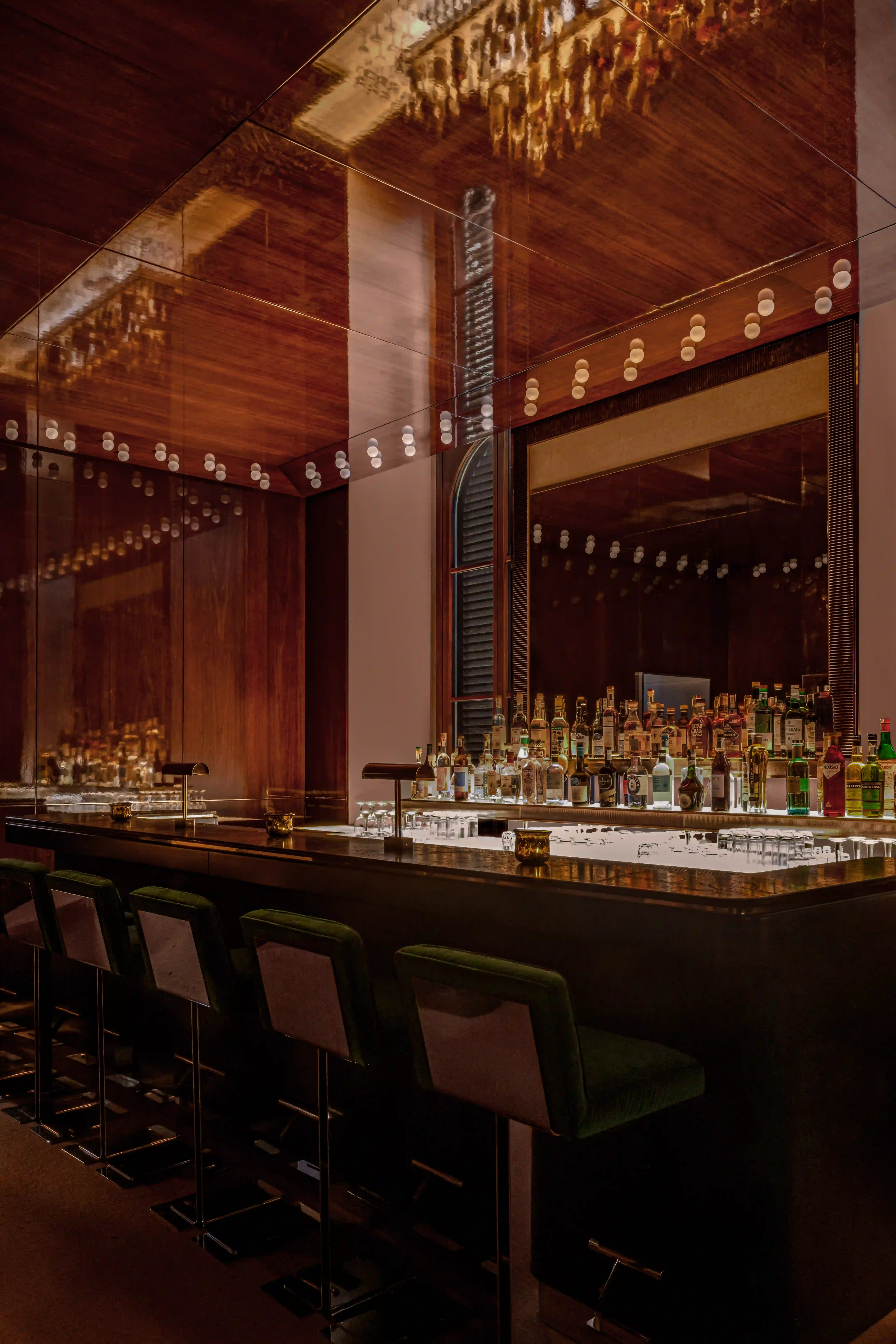 Elegant bar interior featuring a green marble counter, modern bar stools, and warm ambient lighting.
