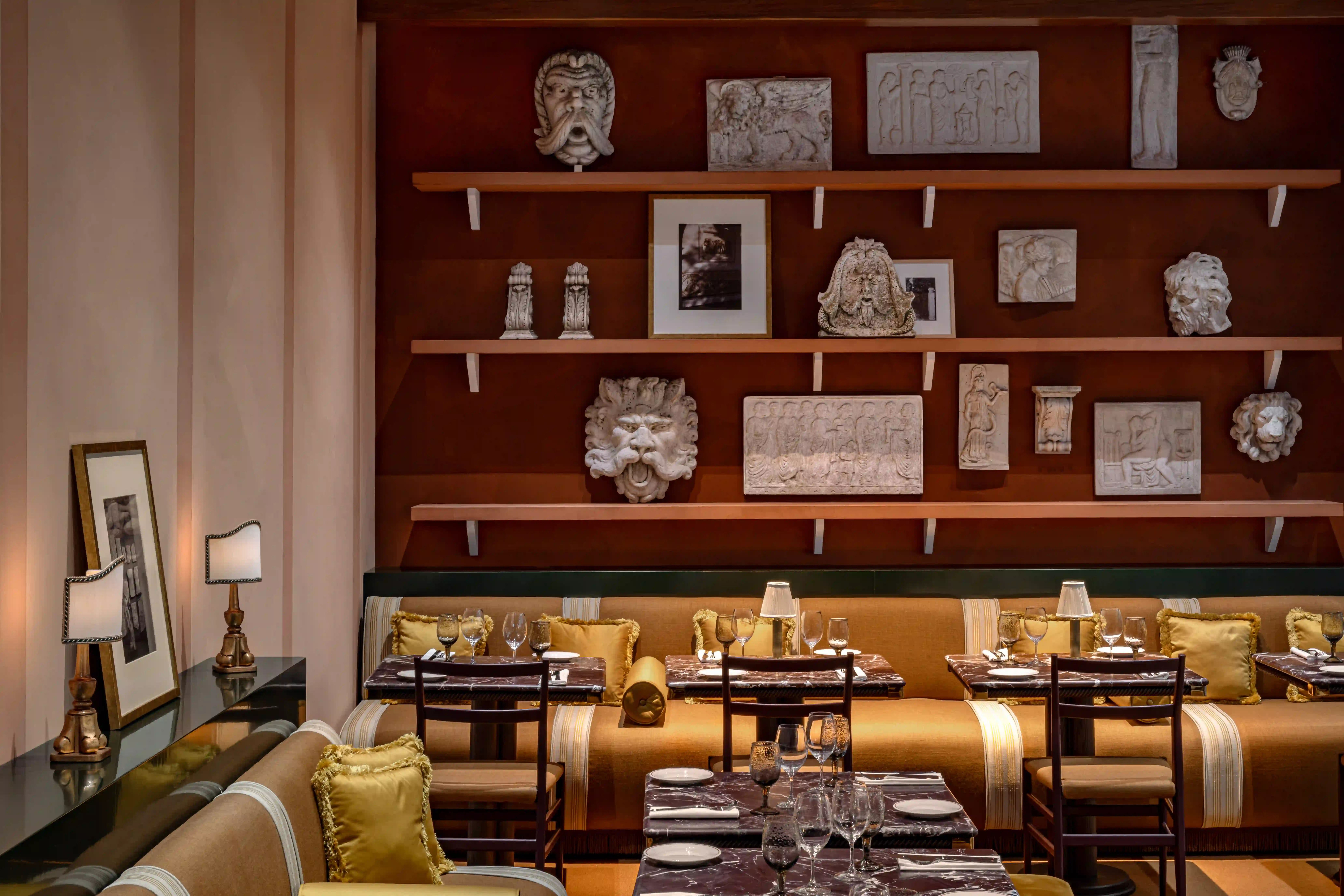 Upscale restaurant interior with wood beams, marble tables, and people dining and a bartender at the bar.