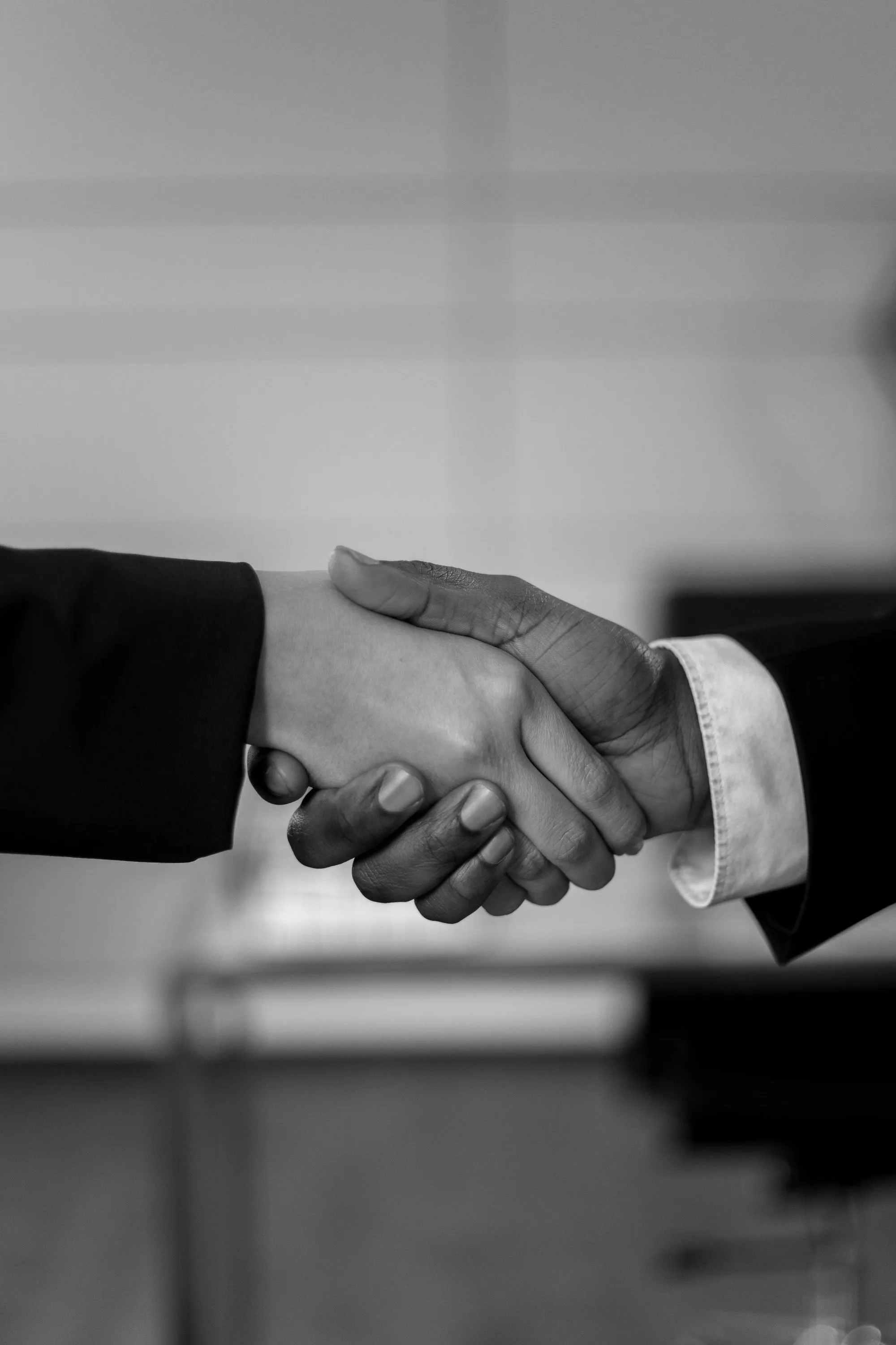 A black and white photo of two people shaking hands.