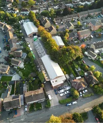 Aerial view of a residential neighborhood with houses, parked cars, and green trees along the streets.