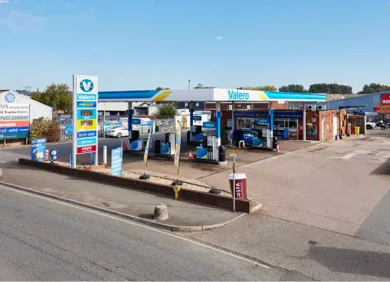 Valero petrol station with multiple fuel pumps and a convenience store under a blue and white canopy.