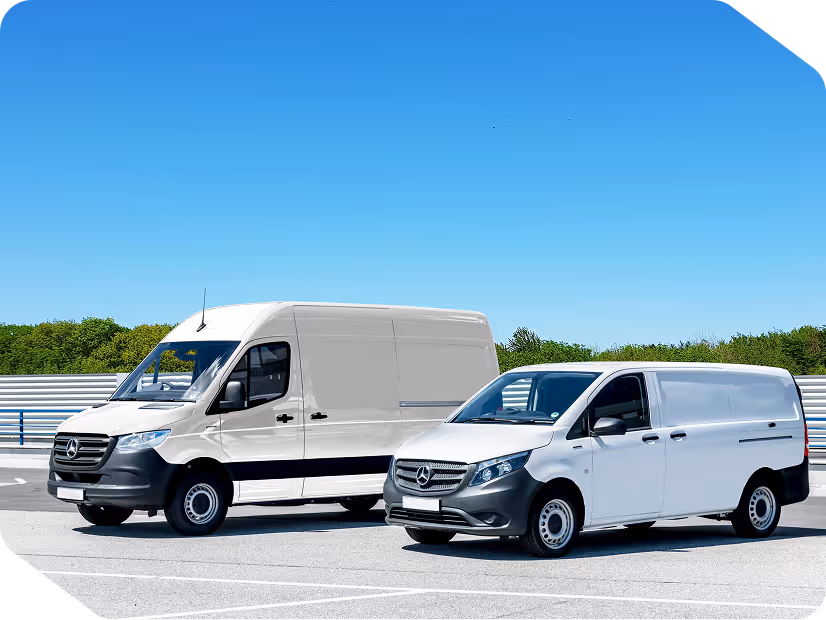 Deux camionnettes blanches Mercedes-Benz stationnées sur un parking extérieur par une journée ensoleillée.