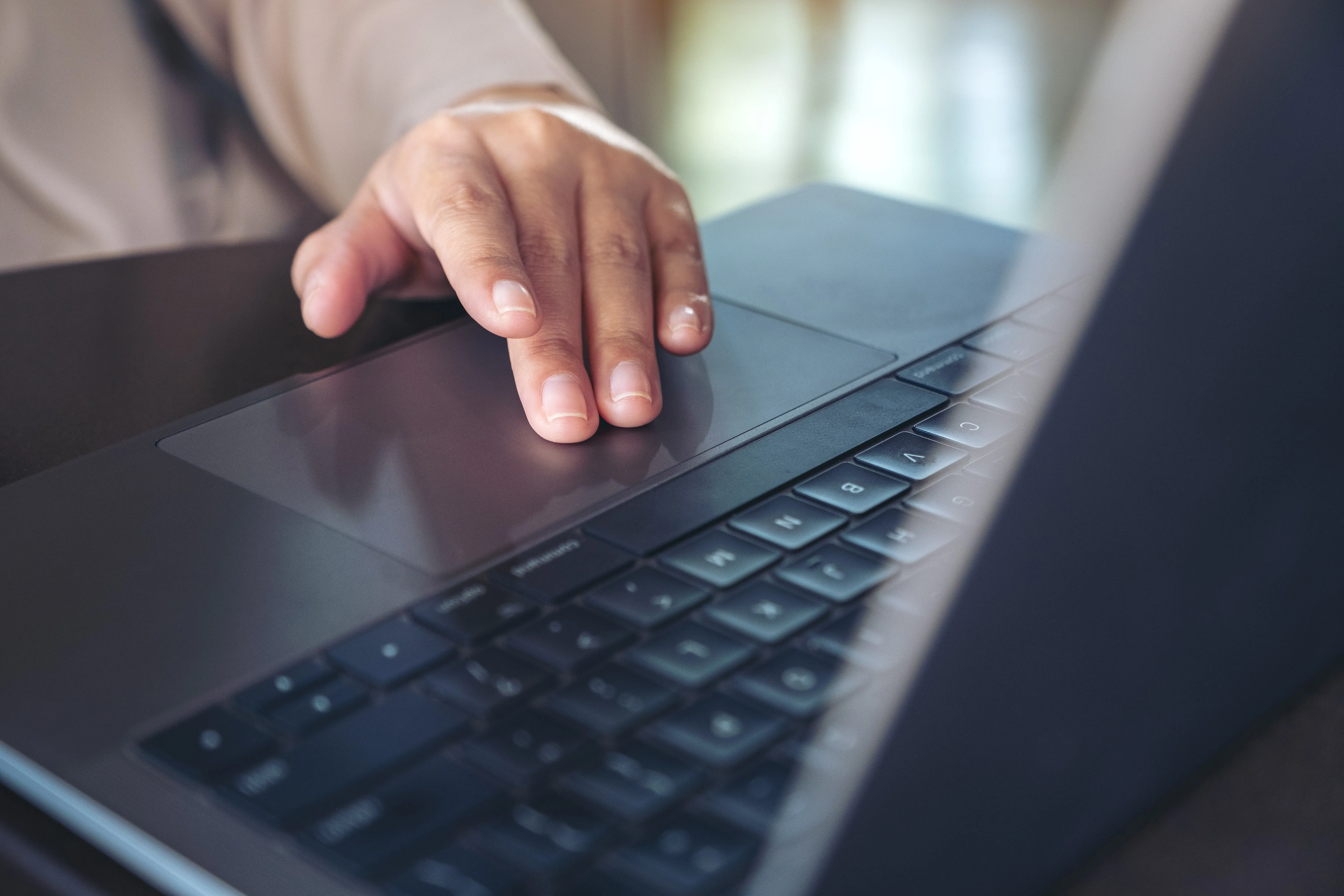 Mano che utilizza il touchpad di un laptop, simbolo di lavoro digitale, tecnologia, produttività, smart working e utilizzo quotidiano del computer.