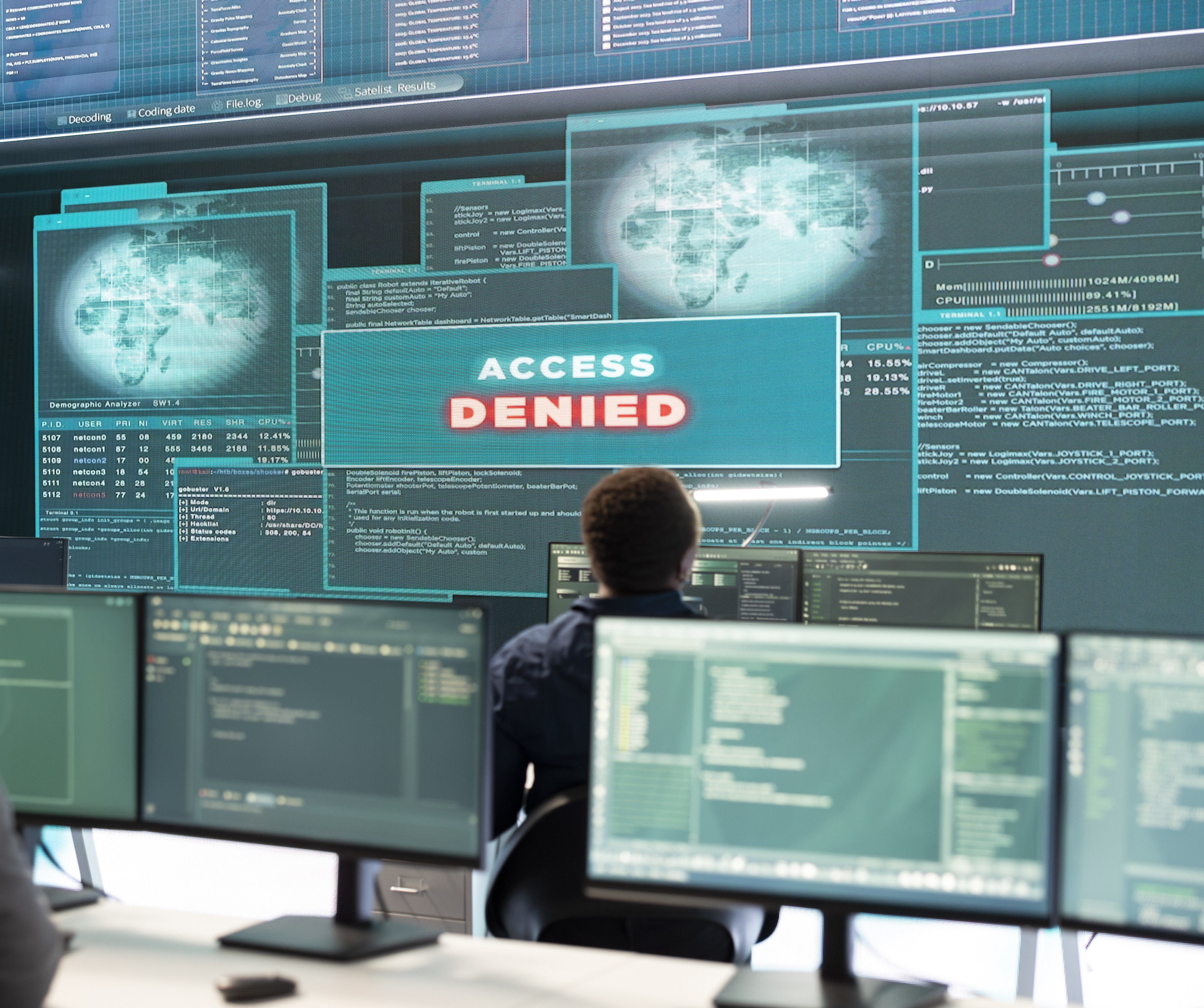 Esperto di cybersecurity davanti a più monitor con avviso “Access Denied”, simbolo di sicurezza informatica, controllo accessi e protezione dei sistemi.