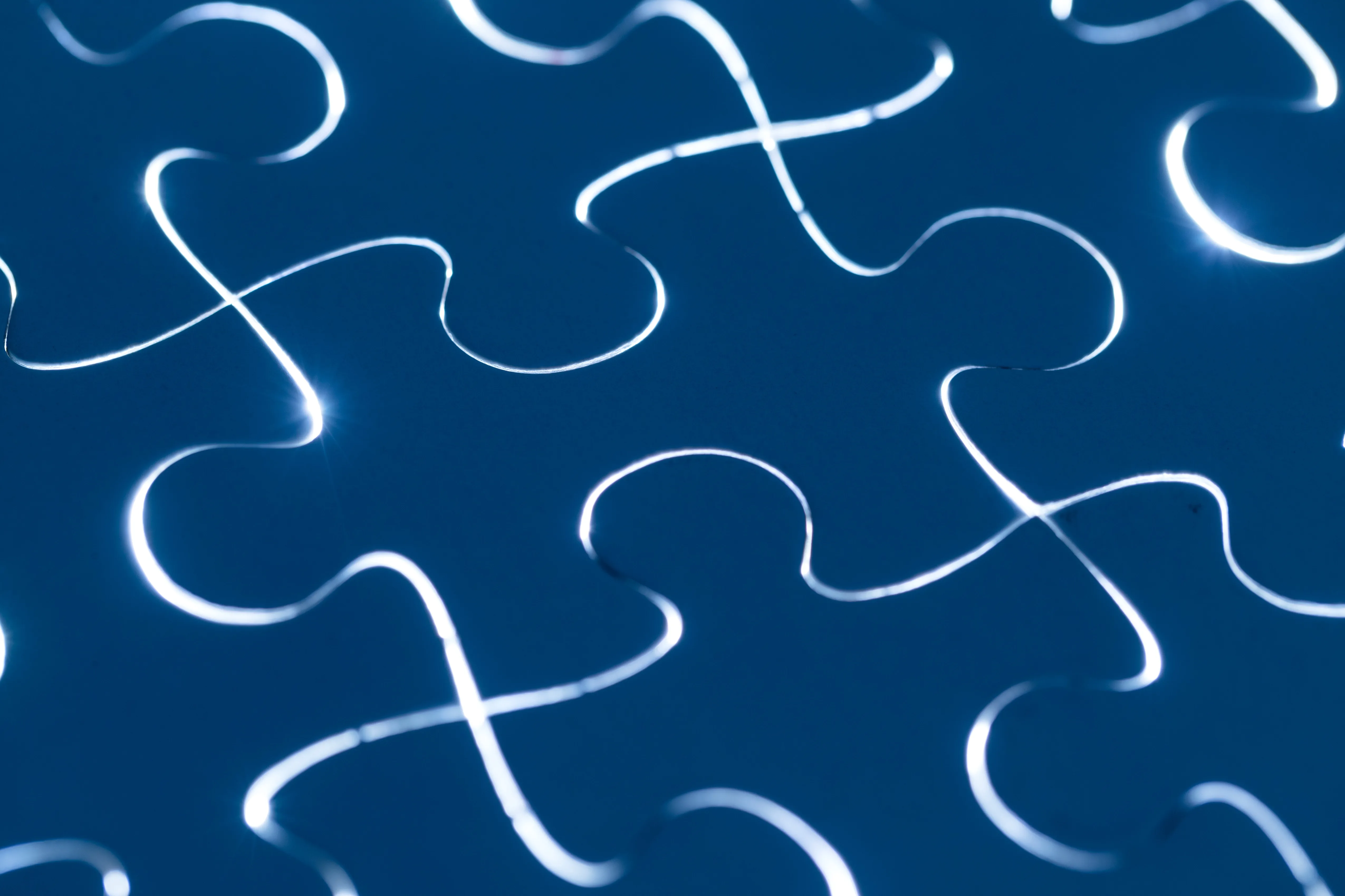Puzzle blu interconnessi con linee luminose, simbolo di connessione, integrazione, collaborazione, tecnologia e soluzioni digitali.