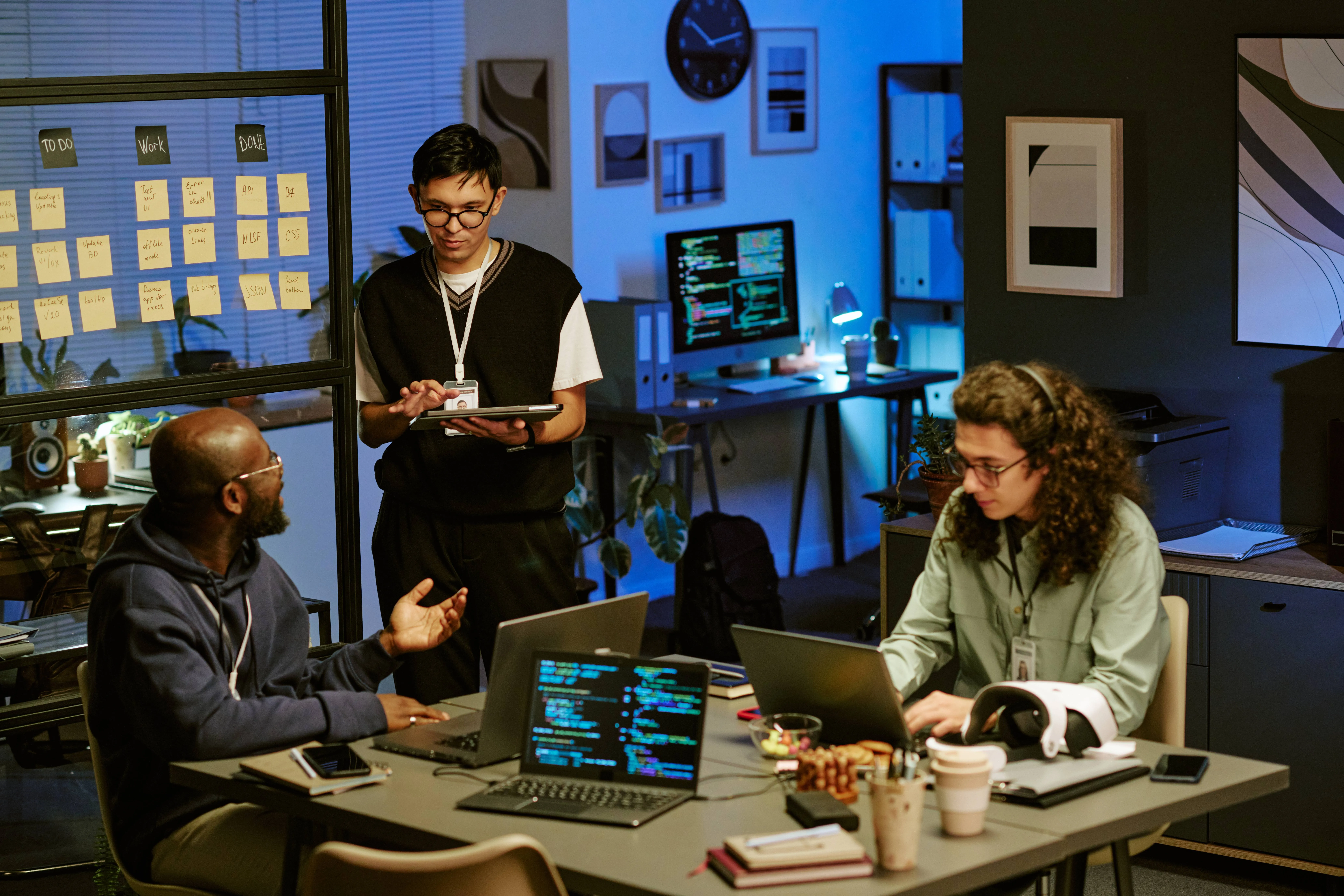 Team di sviluppatori al lavoro in ufficio su laptop e codice, simbolo di programmazione, sviluppo software, collaborazione e innovazione digitale.