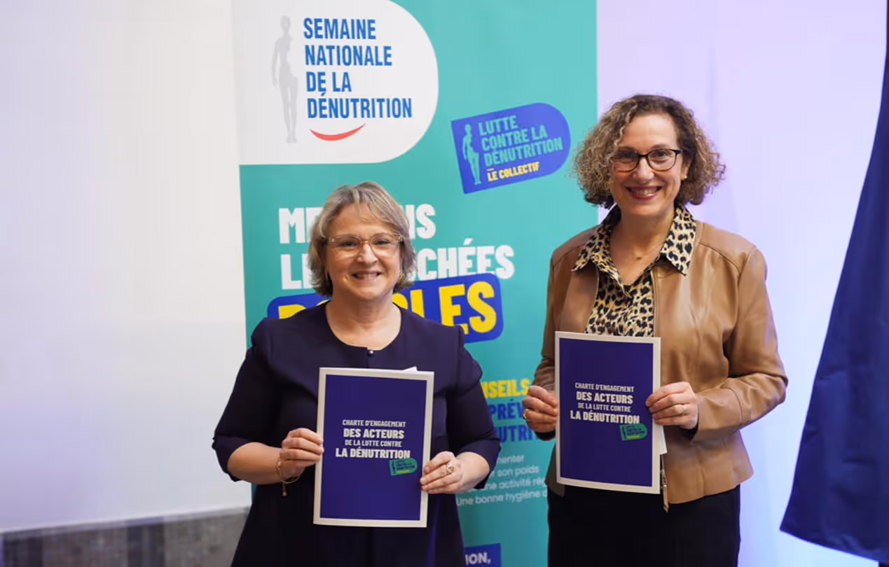 Deux femmes présentant des documents de sensibilisation aux enjeux de la dénutrition lors d'un événement public.
