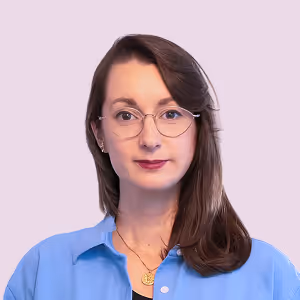 Porträt einer Frau mit Brille und braunen Haaren, die ein blaues Hemd trägt.