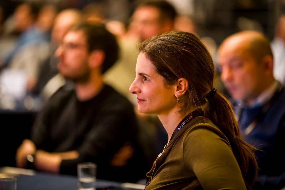 Smiling Positive employee listening attentively among an audience at a corporate event.