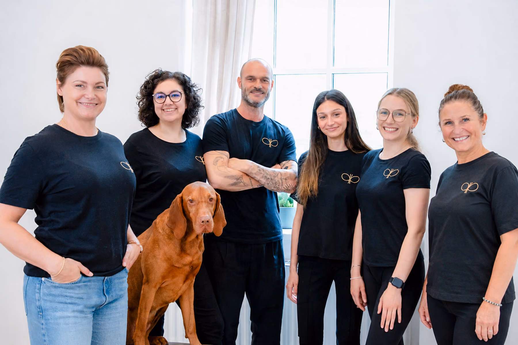 Team der Physiotherapie Pfitzner mit Hund vor weißem Hintergrund