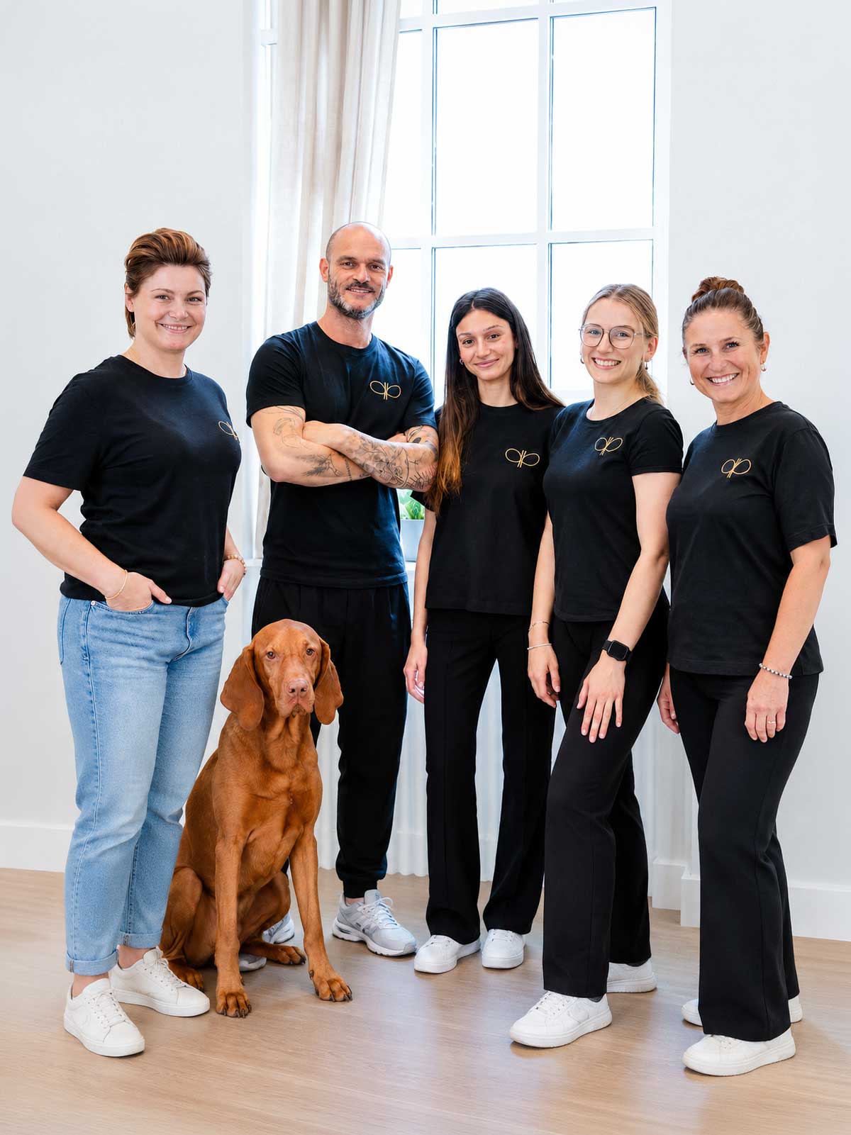 Team der Physiotherapie Pfitzner mit Hund vor weißem Hintergrund