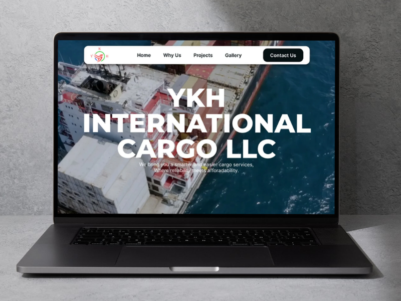 Laptop screen showing YKH International Cargo LLC website with a cargo ship background and menu bar.