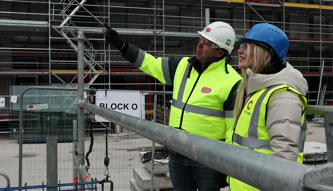 Construction professionals discussing site progress and safety on a large urban development project.