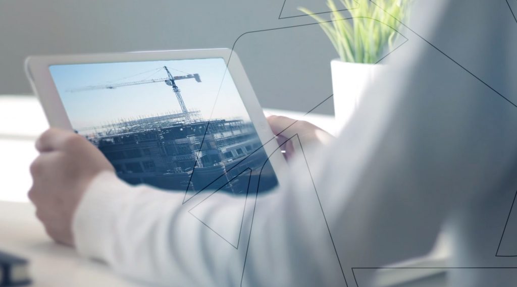 a man holding a tablet that contains a construction site picture