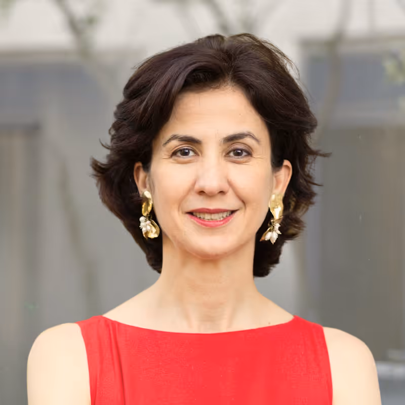 Coach Cristina Pop – Smiling woman with short dark hair wearing gold floral earrings and a red sleeveless top.