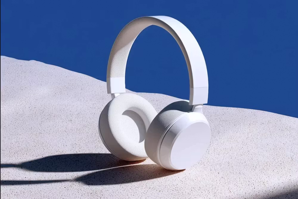 White over-ear headphones placed upright on a textured light surface with a deep blue background.