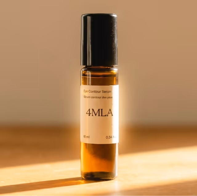 Amber glass bottle of 4MLA Eye Contour Serum with a black cap on a sunlit wooden surface.