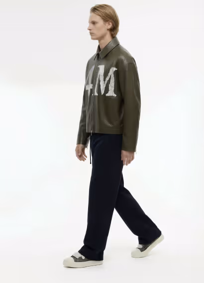 Dark green liquid soap dispenser bottle labeled 'FOURMULA' with a black pump and a leafy plant branch beside it.