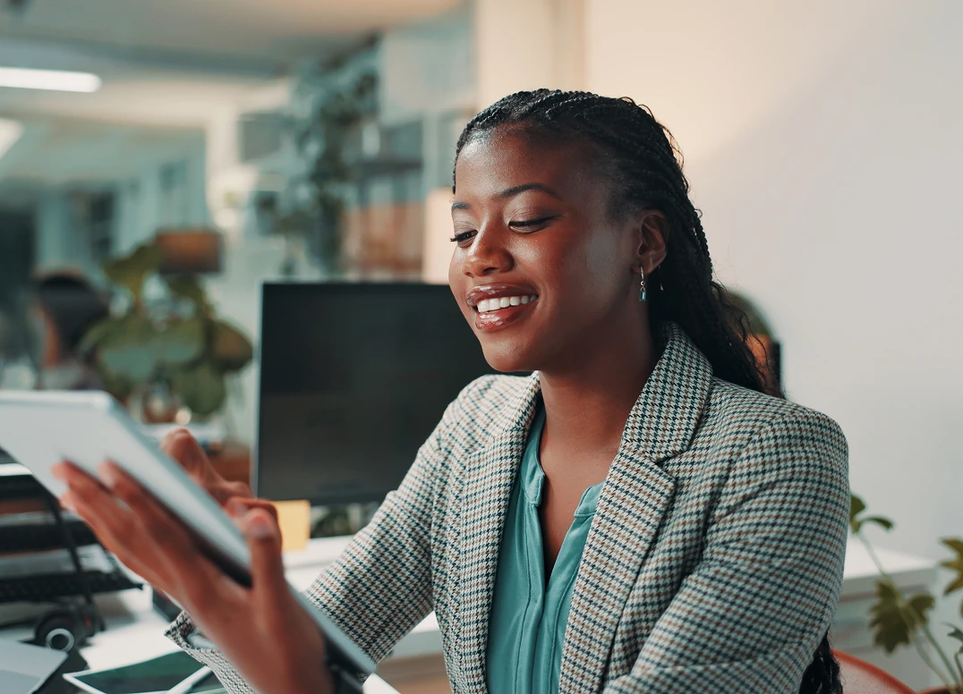 Smiling woman using a tablet in a bright modern office.