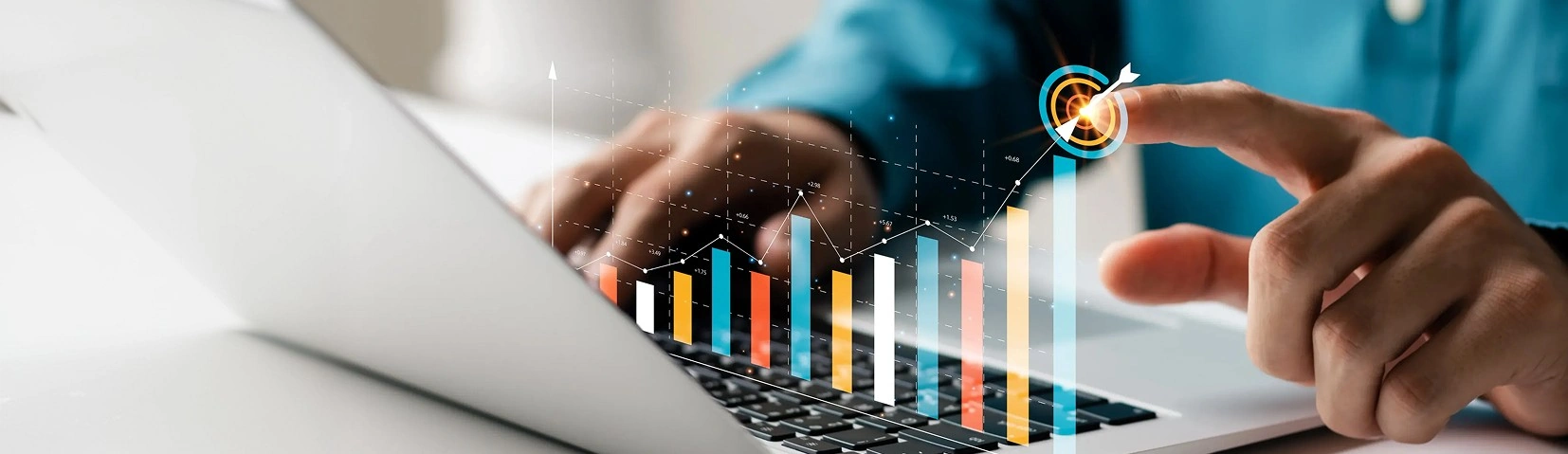 Person using a laptop with a digital bar chart and target graphic overlay on the keyboard.