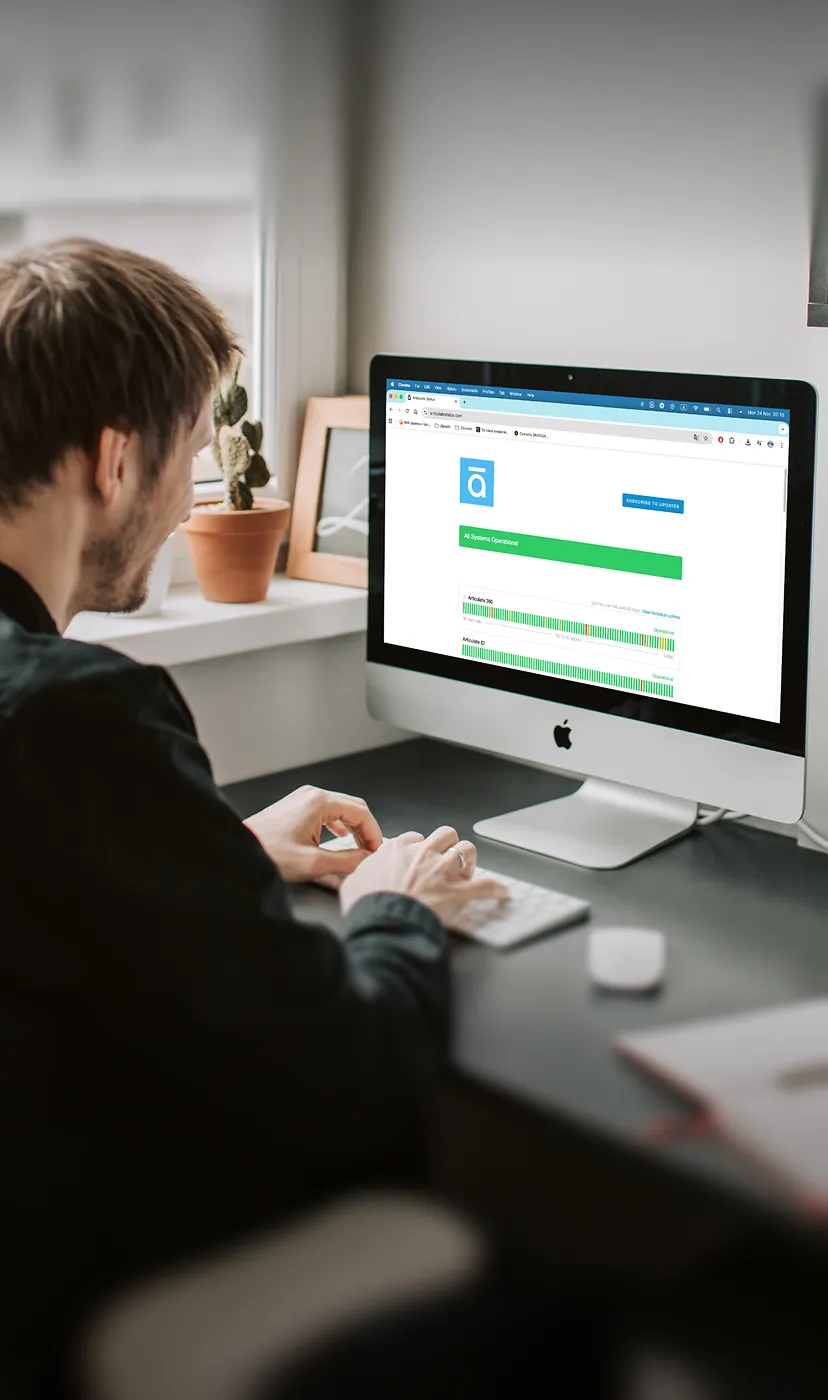 Man typing on keyboard while looking at an iMac displaying a system operations dashboard.