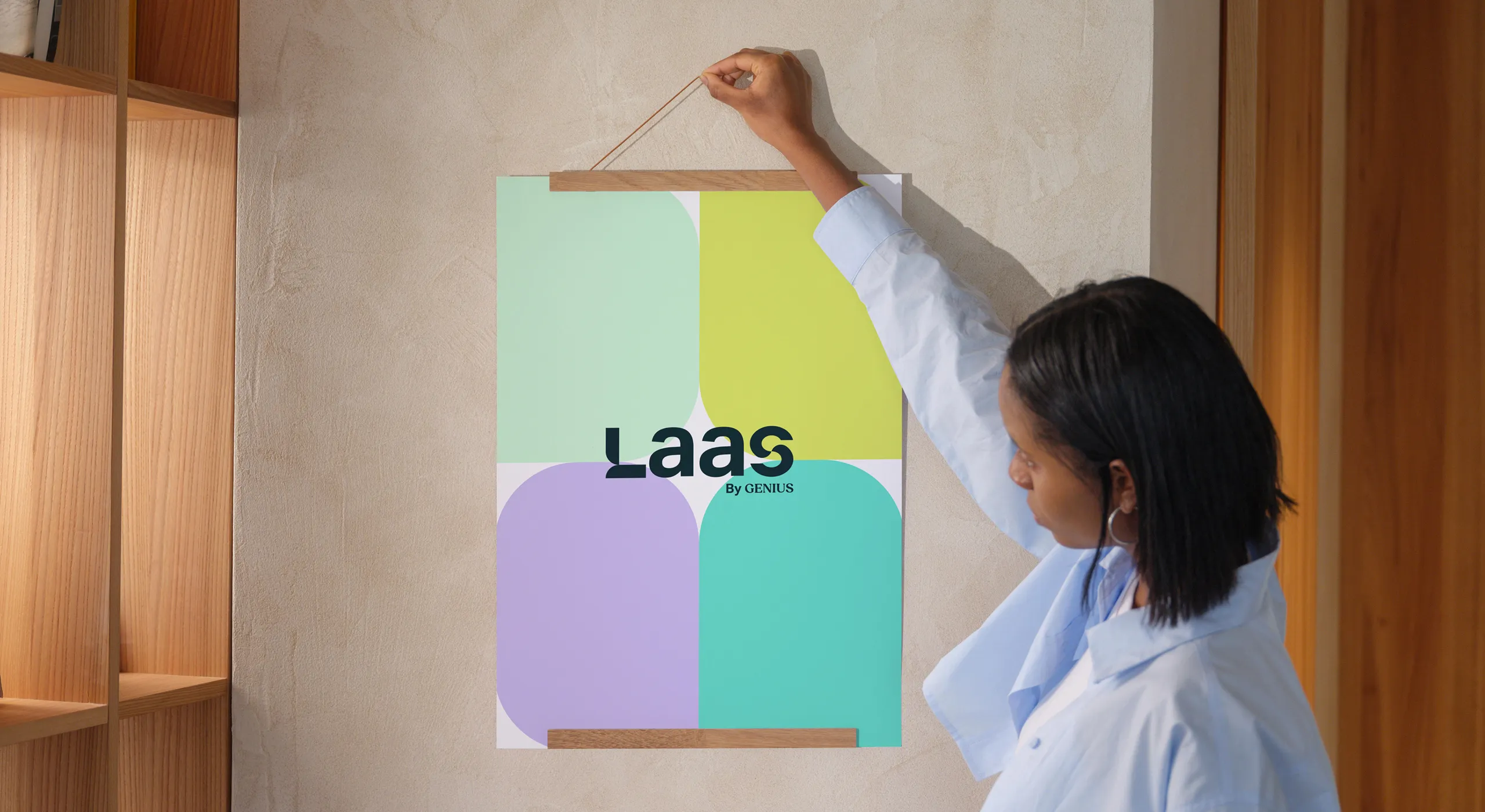 Person hanging a colorful poster on a textured beige wall in a wooden room.