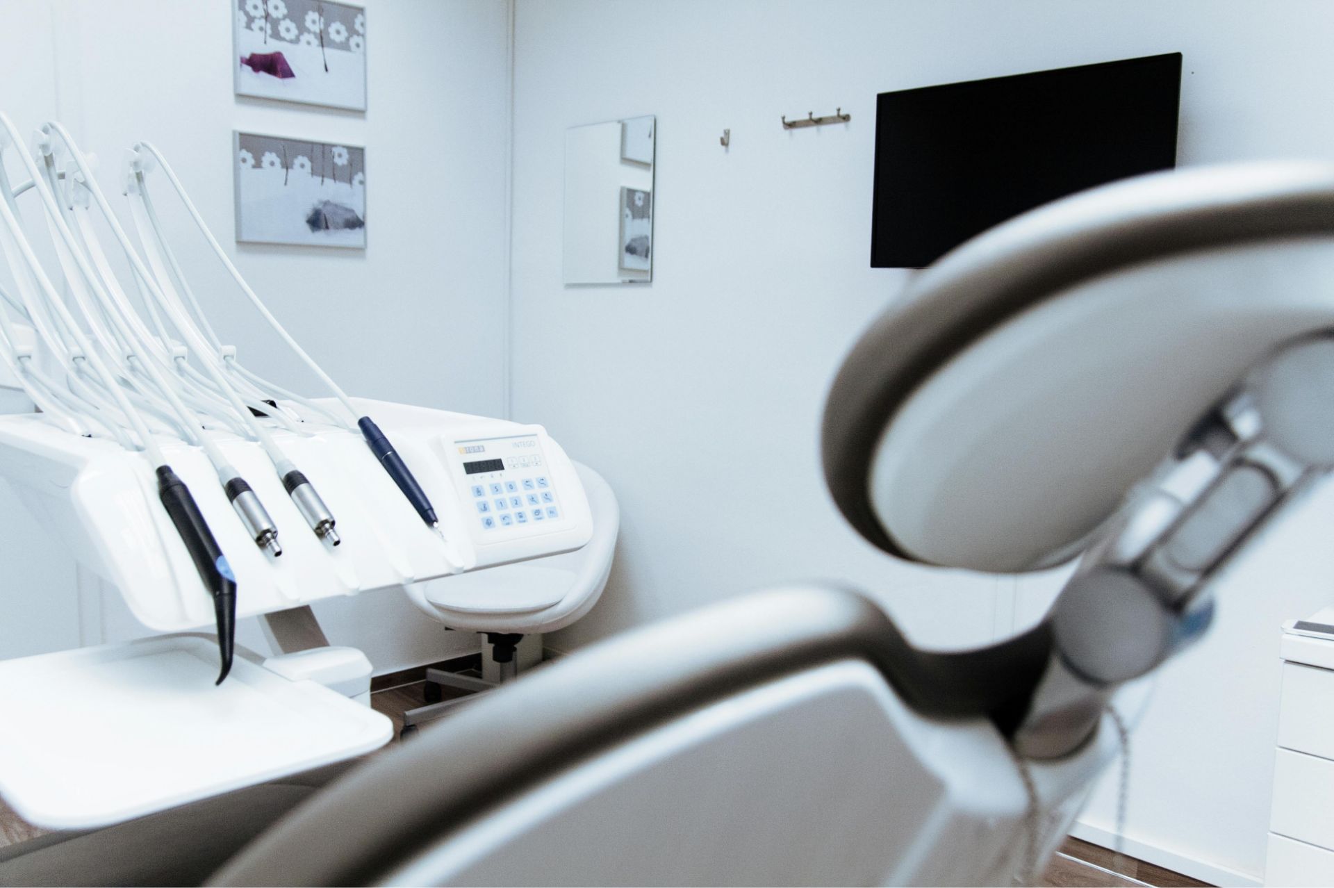 Modern dental office with dental chair, tools, and a wall-mounted TV screen.