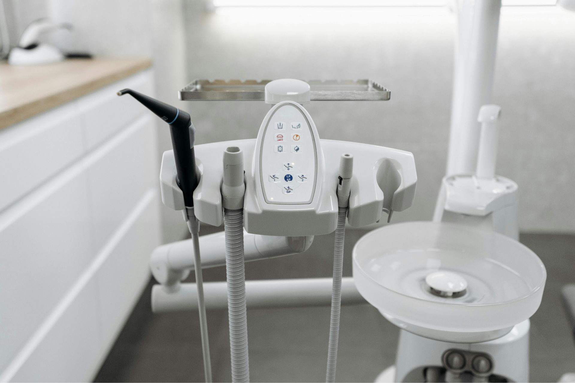 Close-up of dental equipment with control panel and handpieces in a dental clinic.