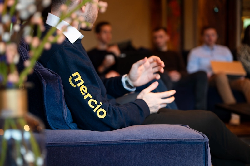 A Mercio employee is talking to his colleagues on a sofa