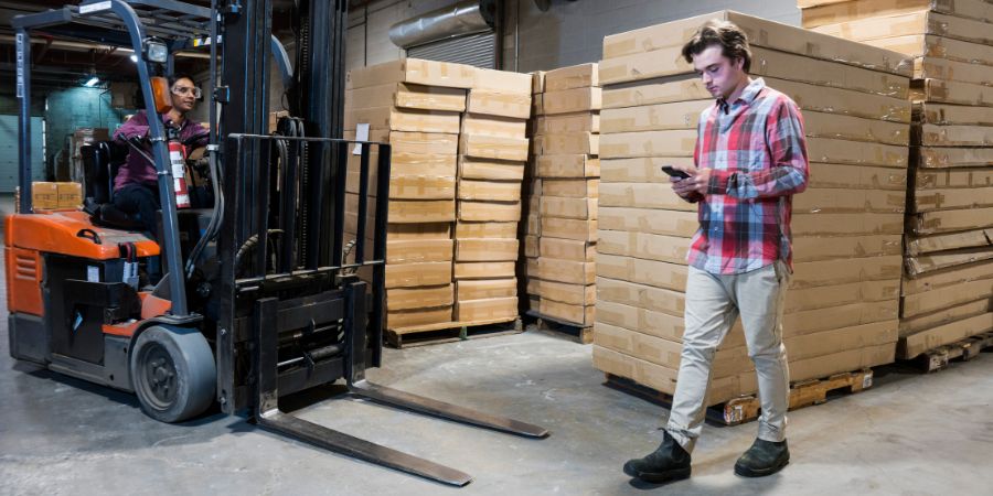 Line of fire exposure: a pedestrian enters an active forklift route while looking at his phone.