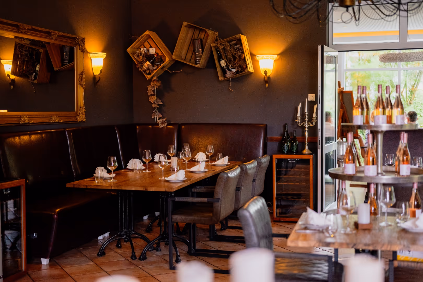 Elegantes Restaurant mit gedecktem Holztisch, Weingläsern, Flaschenregal und offener Tür mit Blick nach draußen.