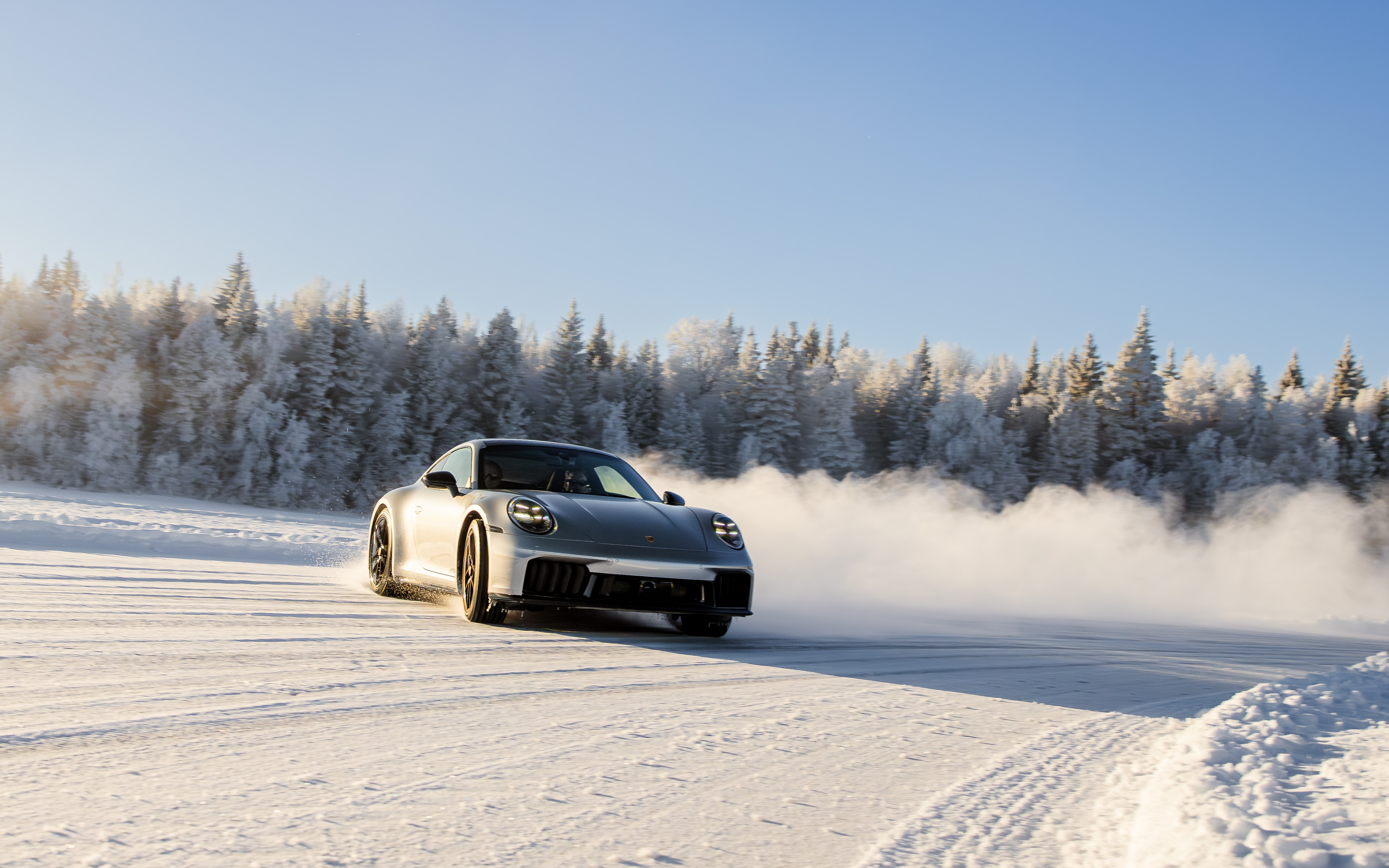 A Porsche kicking up snow while driving on ice in Östersund, Sweden