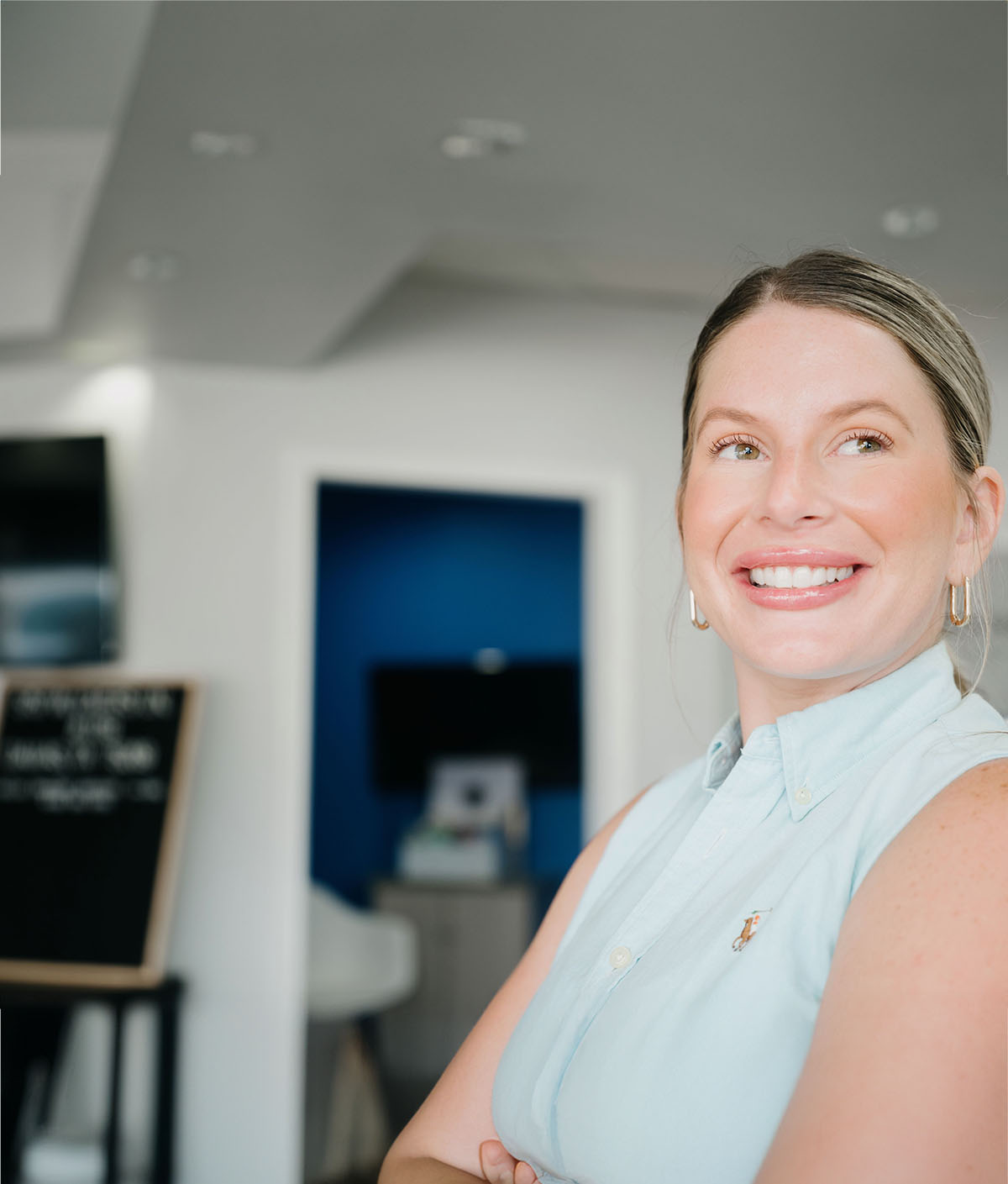 Smiling patient with a bright, natural smile standing inside a modern dental office after an appointment