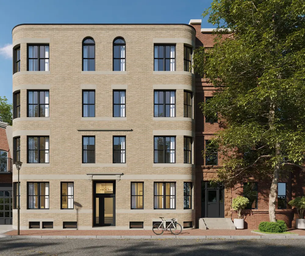 Three-story beige brick building with black-framed windows and a bicycle parked outside on the sidewalk.