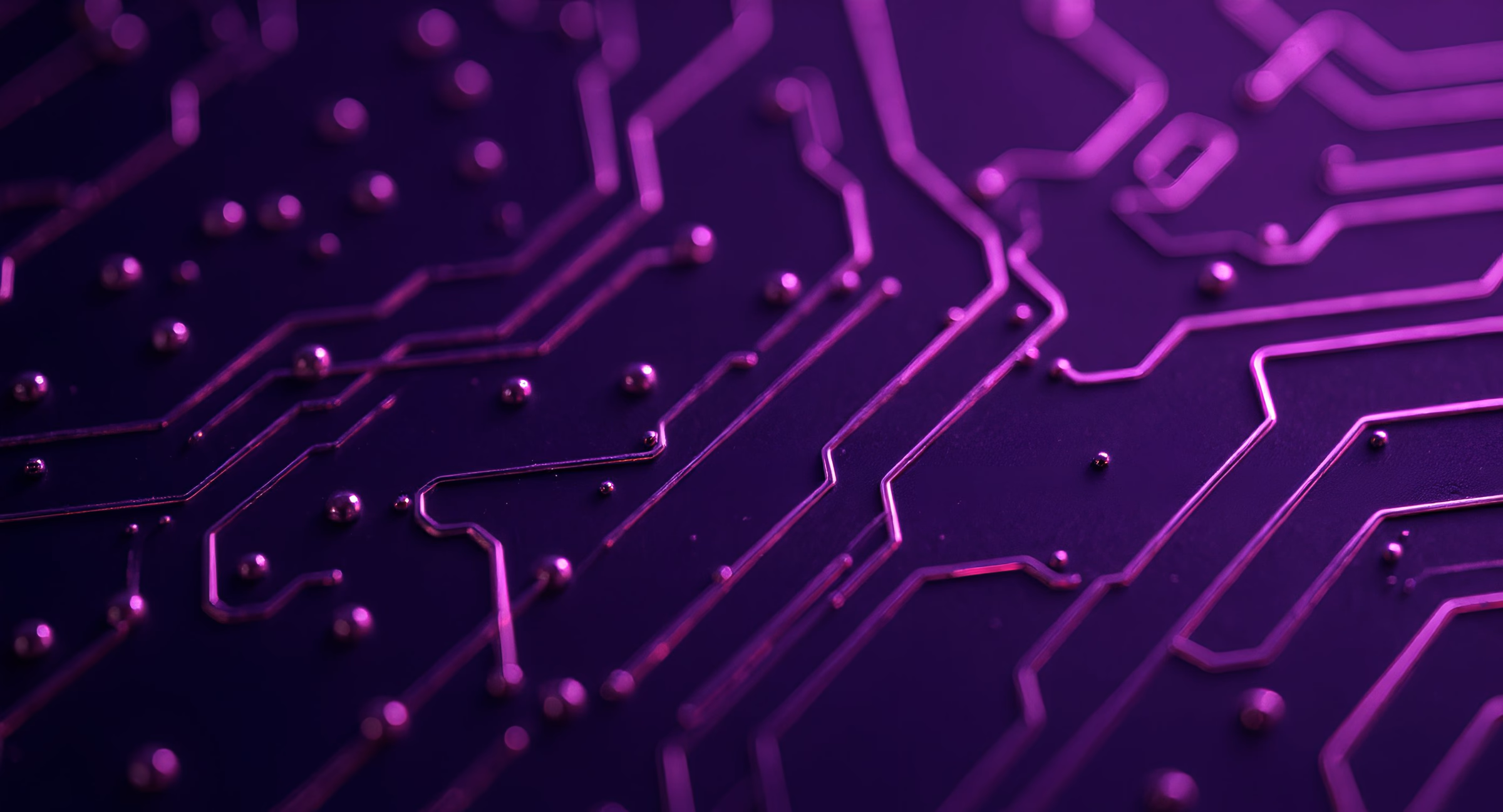 Close-up van een paars verlichte printplaat met metalen verbindingen en soldeerpunten.