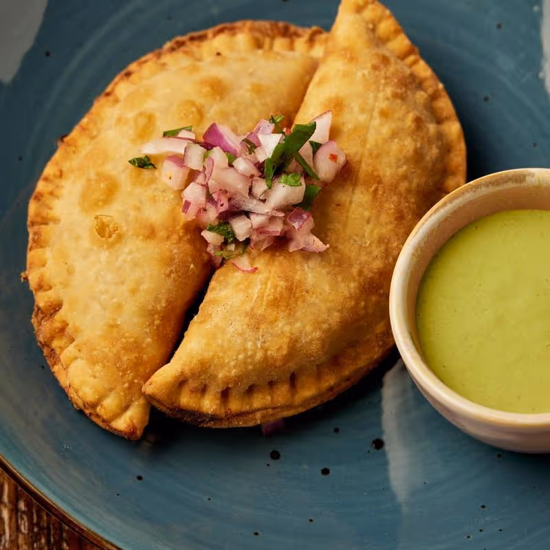 Pulled chicken stew in yellow aji cream sauce, criolla sauce, and green alioli aji