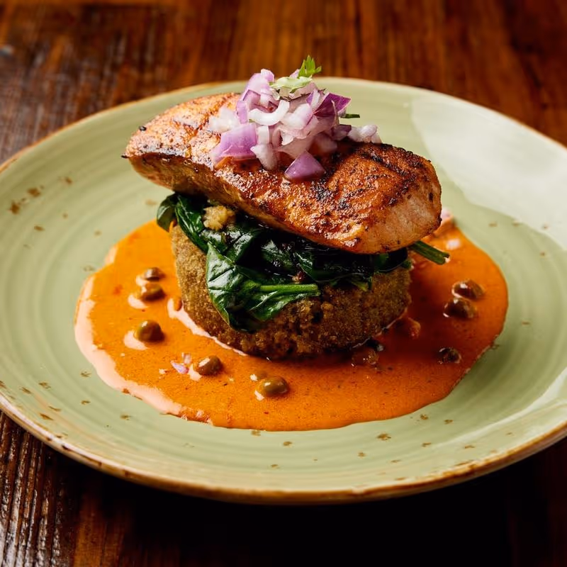 Pan seared salmon, crispy risotto cake, citrus aji panca cream sauce, sautéed spinach, salsa criolla