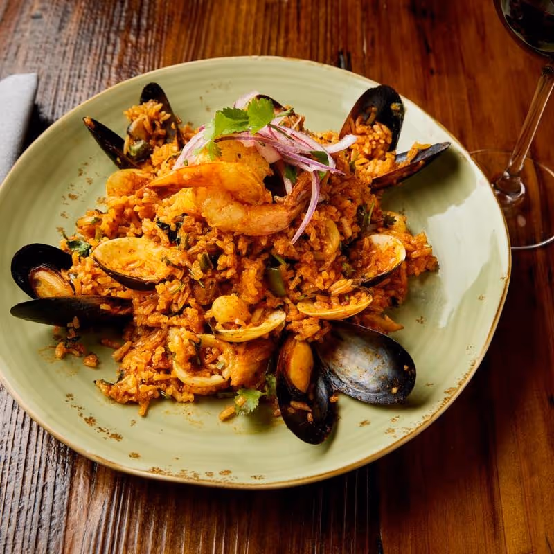 Clams, mussels, shrimp, calamari, scallops & fish with aji panca rice, cilantro, green peas, peppers, salsa criolla