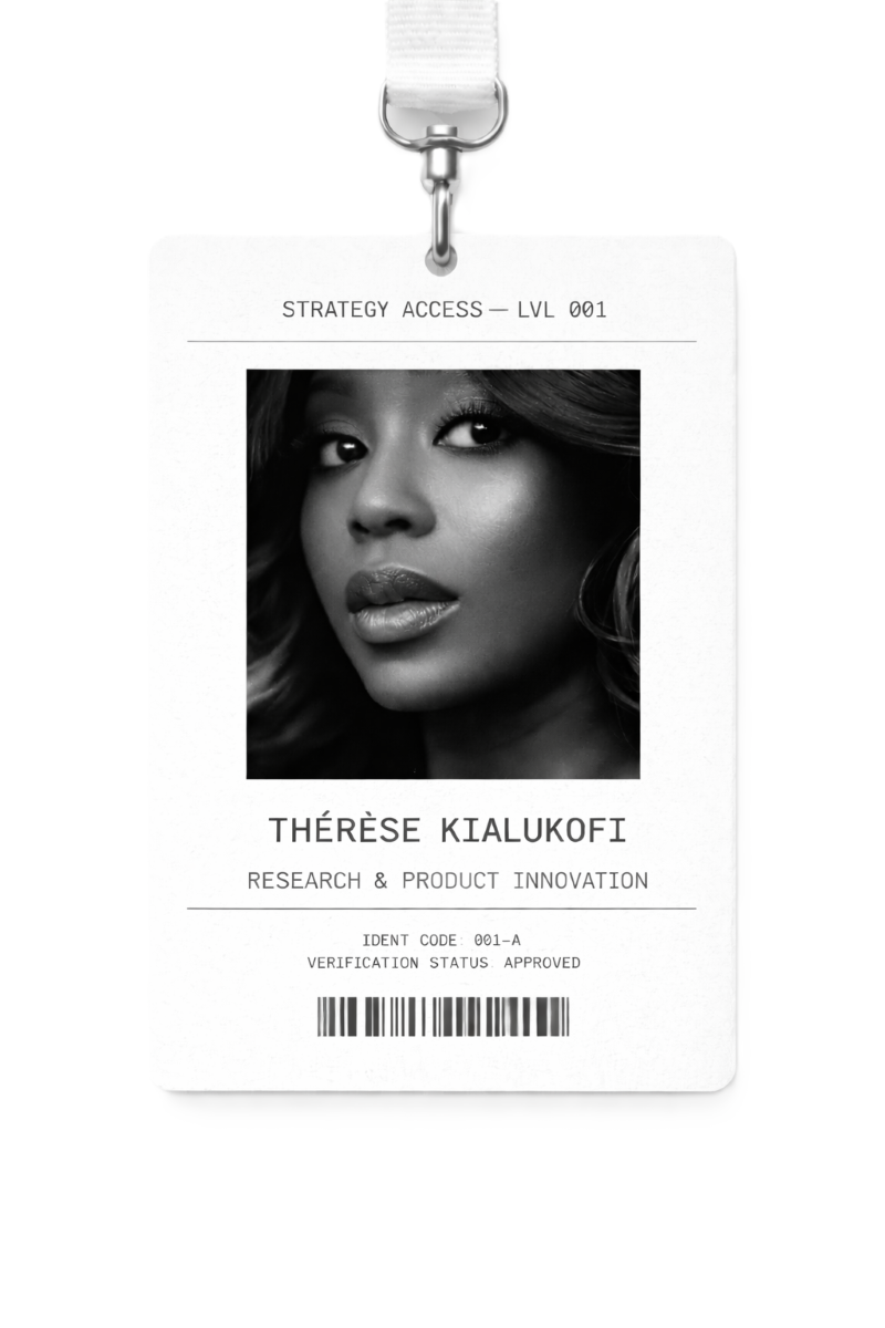 Vertical black-and-white ID badge on a pure white background, hanging from a white lanyard with a metal clip. The badge has a matte white, lightly textured surface with thin black rule lines. At the top, monospaced text reads ‘STRATEGY ACCESS — LVL 001.’ Centered is a tightly cropped, monochrome editorial portrait of a Black woman’s face with soft cinematic lighting and high contrast. Below the photo, monospaced text reads ‘THÉRÈSE KIALUKOFI’ and ‘RESEARCH & PRODUCT INNOVATION.’ Beneath this are small monospaced lines reading ‘IDENT CODE: 001-A’ and ‘VERIFICATION STATUS: APPROVED,’ followed by a centered black barcode at the bottom.