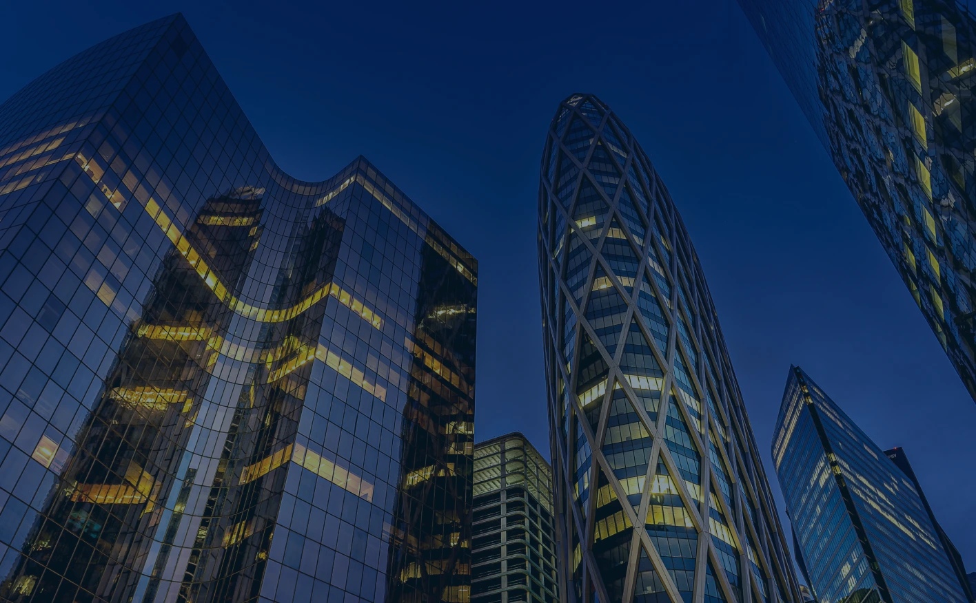 Night view of modern glass skyscrapers with illuminated windows, symbolizing innovation and corporate leadership
