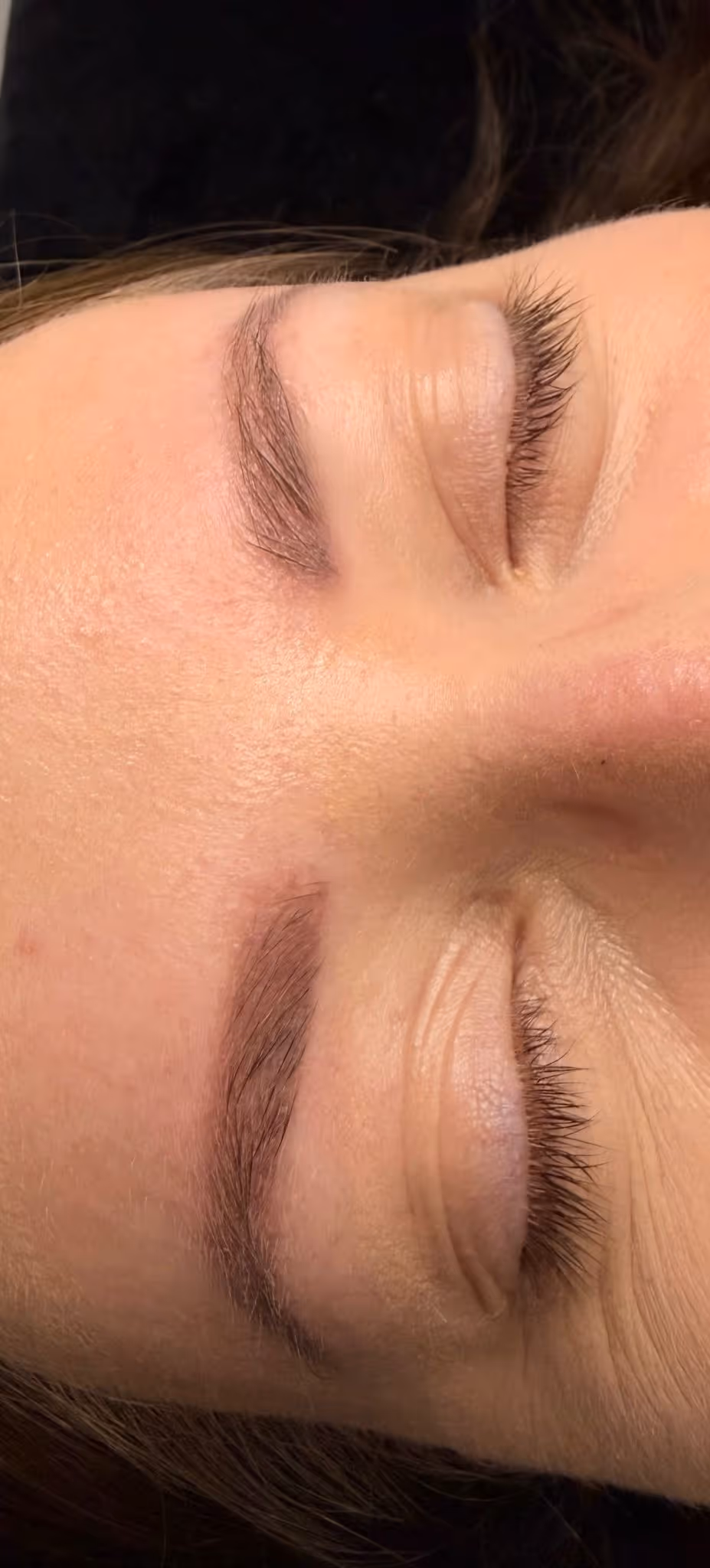 Nahaufnahme eines Gesichts mit geschlossenen Augen und gepflegten Augenbrauen.