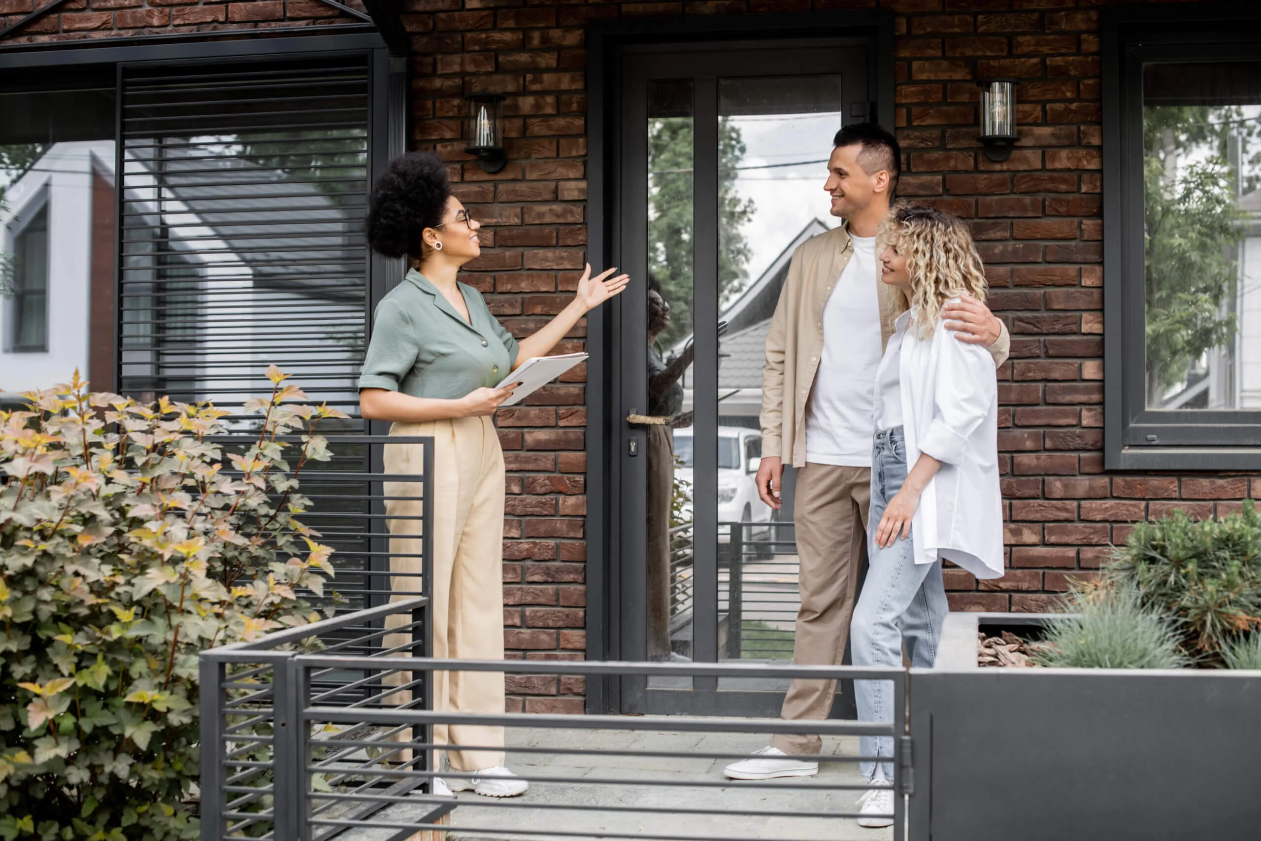 Real estate agent wth clients in front of house