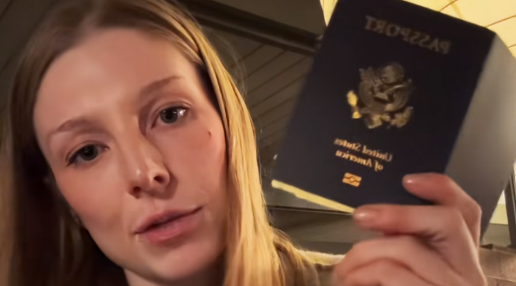 Blonde actress Hunter Schafer holds up passport to camera