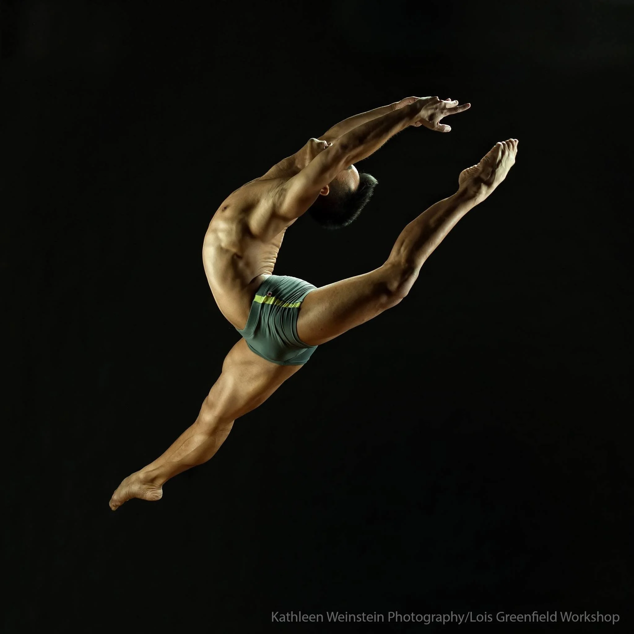 Jason leaps in mid air, doing the splits impressively in nothing but tight green shorts. A watermark credits Kathleen Weinstein Photography / Lois Greenfield Workshop