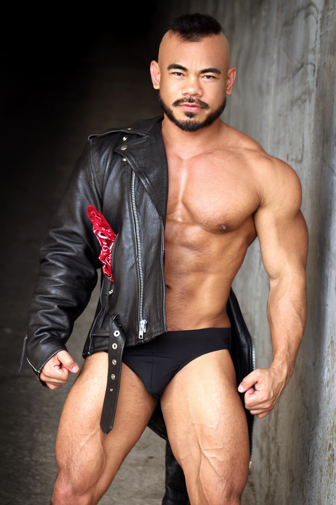 Jason Luna looks steamy and intimidating posed in a black leather jacket with a red bandana poking out of the pocket